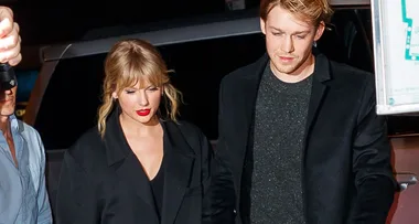 A person with blonde hair and red lipstick walks beside another person with blonde hair at night.