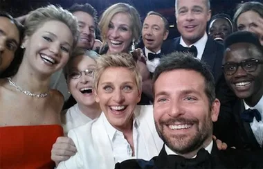 A group selfie taken at the Oscars with several happy celebrities including Ellen DeGeneres, Bradley Cooper, and Jennifer Lawrence.