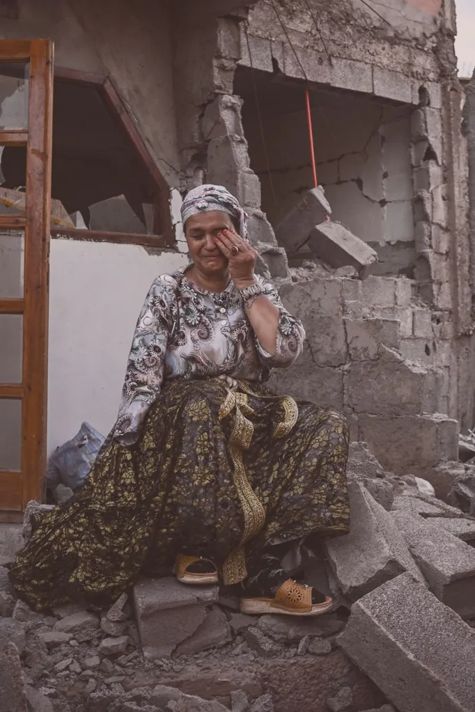 A survivor of the deadly 6.8-magnitude September 8 earthquake cries as she sits on the rubble of her damaged house, in the mountain village of Moulay Brahim in al-Haouz province in central Morocco