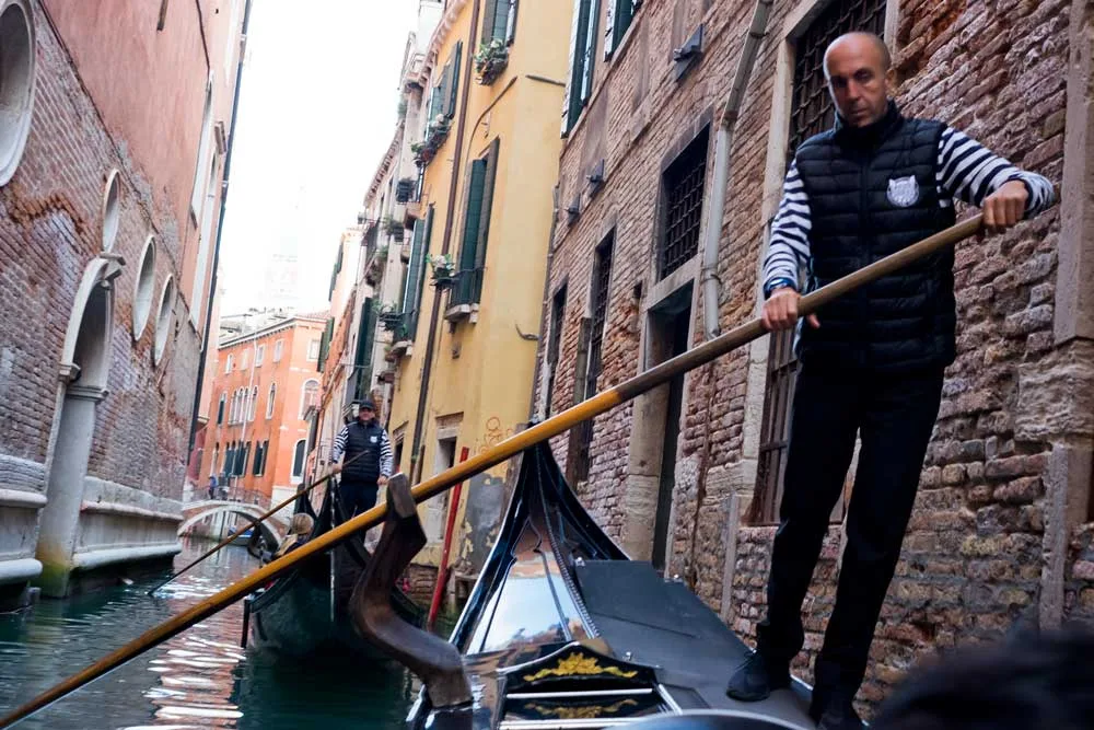 Man pushing a gondola through Venice