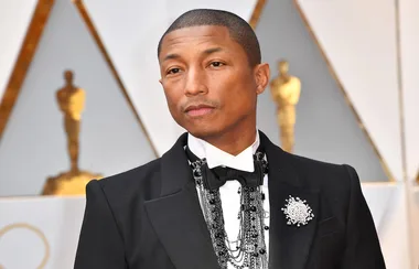 Pharrell is wearing a giant necklace. Because he can