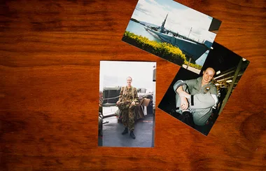 Three military-themed photos on a wooden table; a soldier, a ship, and a person in uniform smiling.