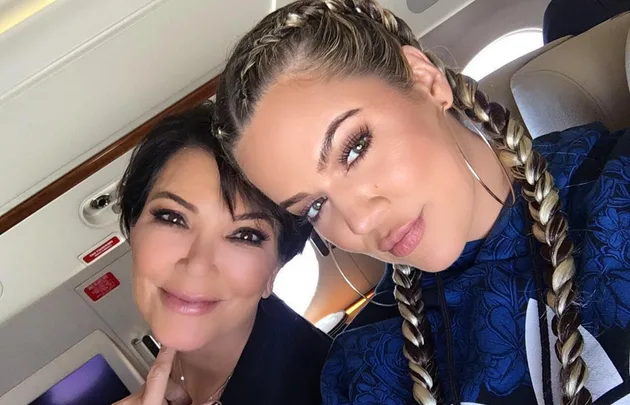 Two women taking a selfie inside a private jet; one has braided hair and hoop earrings.