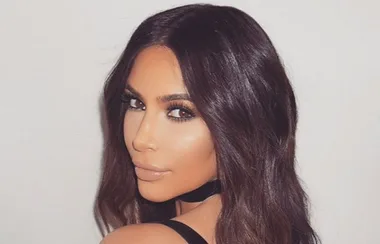 I don't know who this is, but the image shows a woman with long dark hair, wearing a black choker and looking over her shoulder.