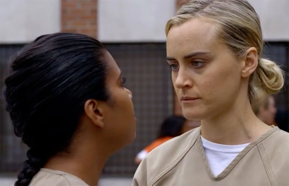 Two women in orange prison uniforms facing each other intensely, scene from "Orange is the New Black."
