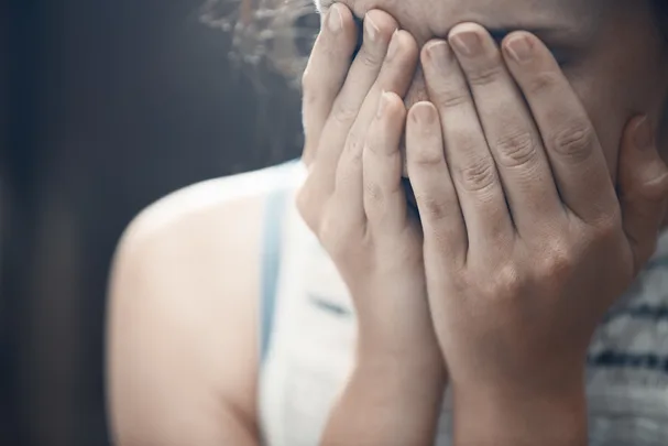 A person covers their face with their hands, expressing distress or sadness.