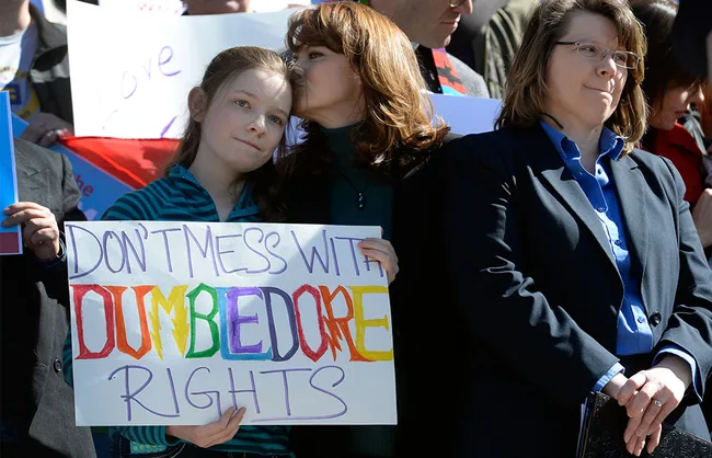 Protesters holding a sign reading "Don't Mess with Dumbledore Rights" at a rally.