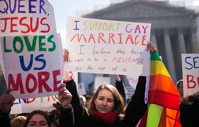 Protesters hold signs supporting gay marriage and LGBTQ+ rights outside a government building.