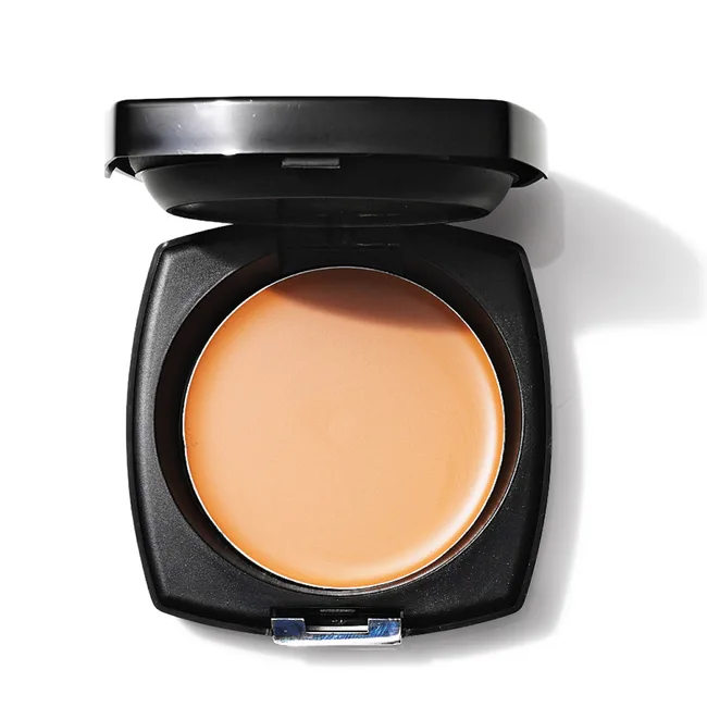 Open compact cream foundation in a black case on a white background.