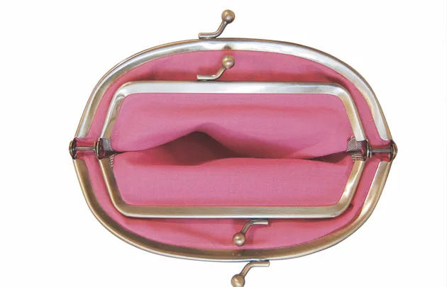 Open vintage pink coin purse with metal frame, viewed from above.