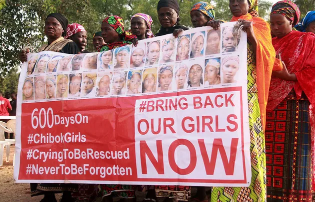 Women hold a banner with photos of missing Chibok girls, urging: "Bring Back Our Girls Now," highlighting 600 days missing.