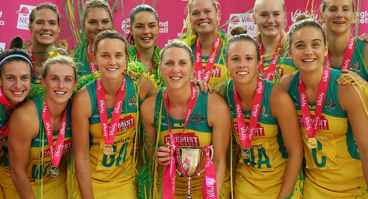 Australian women's netball team celebrating with medals and a trophy after winning a tournament.