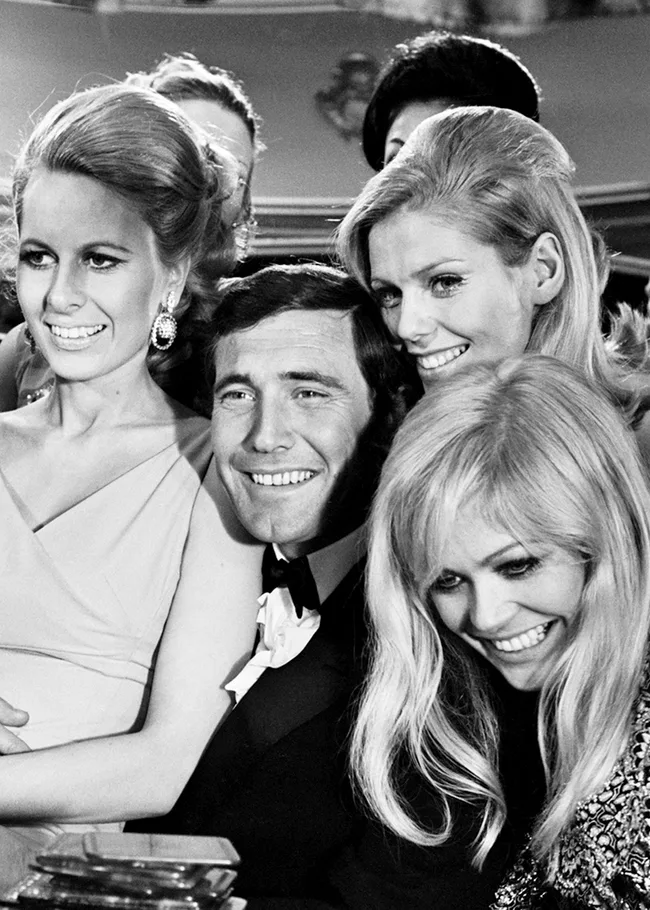 Four smiling individuals posing closely in a black and white group photo.