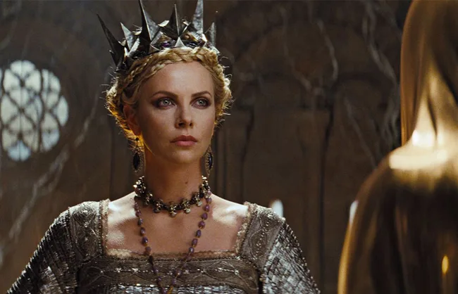 "Character wearing a spiked crown and ornate jewelry, standing in a dimly lit room."