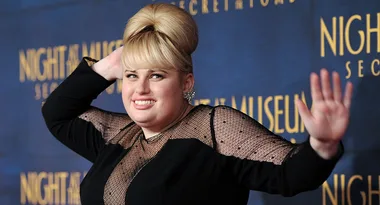 A person poses playfully at the "Night at the Museum: Secret of the Tomb" premiere, smiling in front of a themed background.