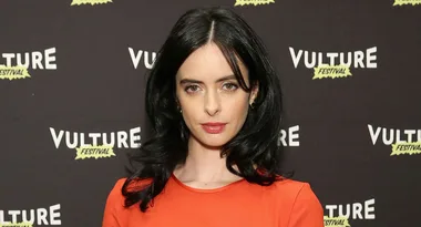 A person in an orange outfit at Vulture Festival, standing before a backdrop with the festival's name.