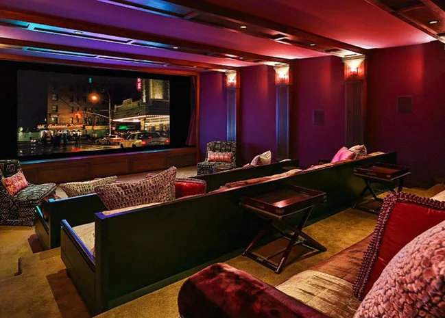 Luxurious home theater with plush seating, dim lighting, and a large screen displaying an urban night scene.