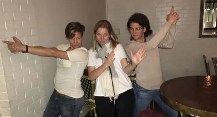 Three people posing playfully with finger guns in a casual setting.