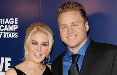 Two people smiling standing in front of a backdrop with text "Marriage Boot Camp: Reality Stars."