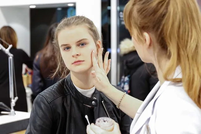 "Person applying makeup on woman's face in a store setting."