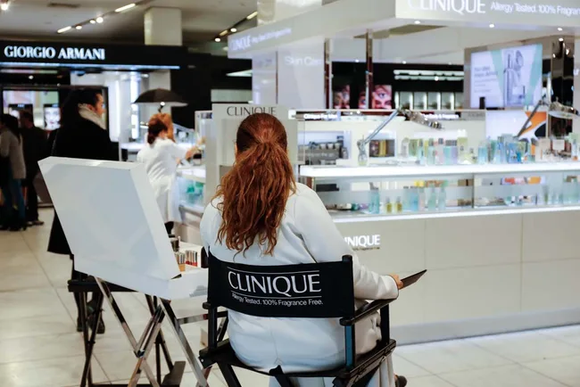 Clinique booth in a department store, with a staff member seated in a director's chair.