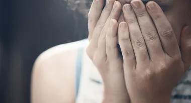 Person covering face with hands, appearing distressed.