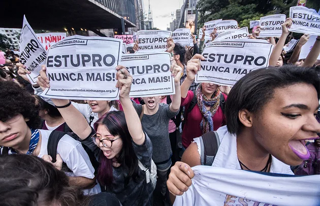 Protesters holding signs reading "Estupro Nunca Mais!" during a demonstration in a city street.