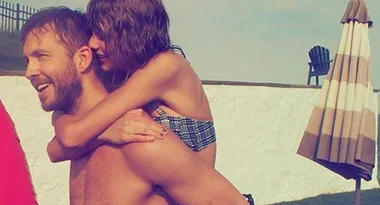 A woman in a swimsuit playfully gives a man a piggyback ride by a poolside during a sunny day, with an umbrella in the background.