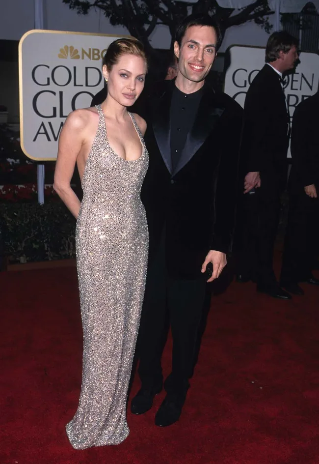 Man and woman on the red carpet at NBC Golden Globe Awards, with a sign in the background.