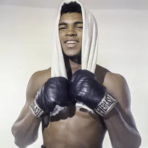 Young boxer with gloves and towel over head, smiling confidently.