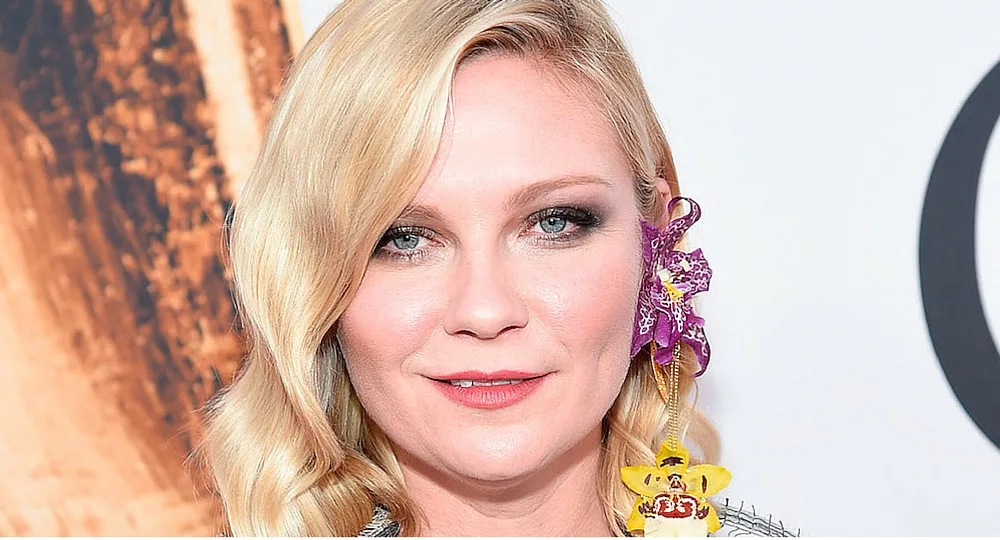 ```plaintext
Woman with blonde hair and floral accessory, smiling at camera.
```