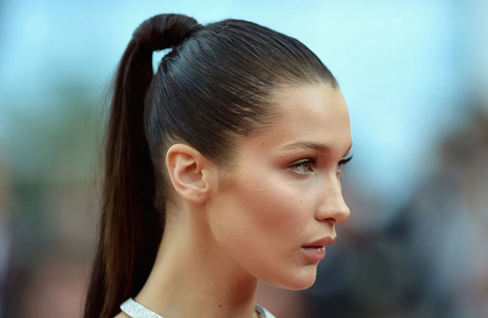 A person with a sleek high ponytail on a blurred background, looking focused and elegant.