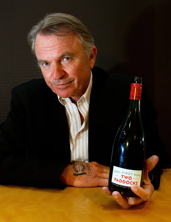 Person holding a bottle of Two Paddocks 2008 Pinot Noir wine with a dark background.