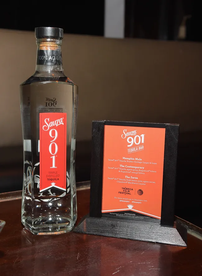 Bottle of Sauza 901 Tequila next to a menu with cocktail recipes on a table.