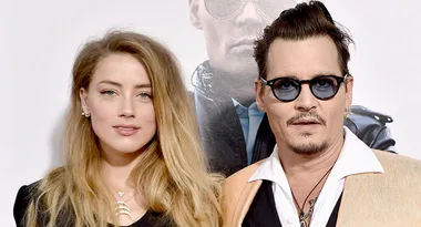 Two individuals posing together at an event, one with long hair and one wearing sunglasses.