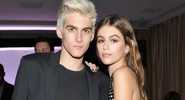 Young man with short blonde hair and young woman with long brown hair posing together at an indoor event.