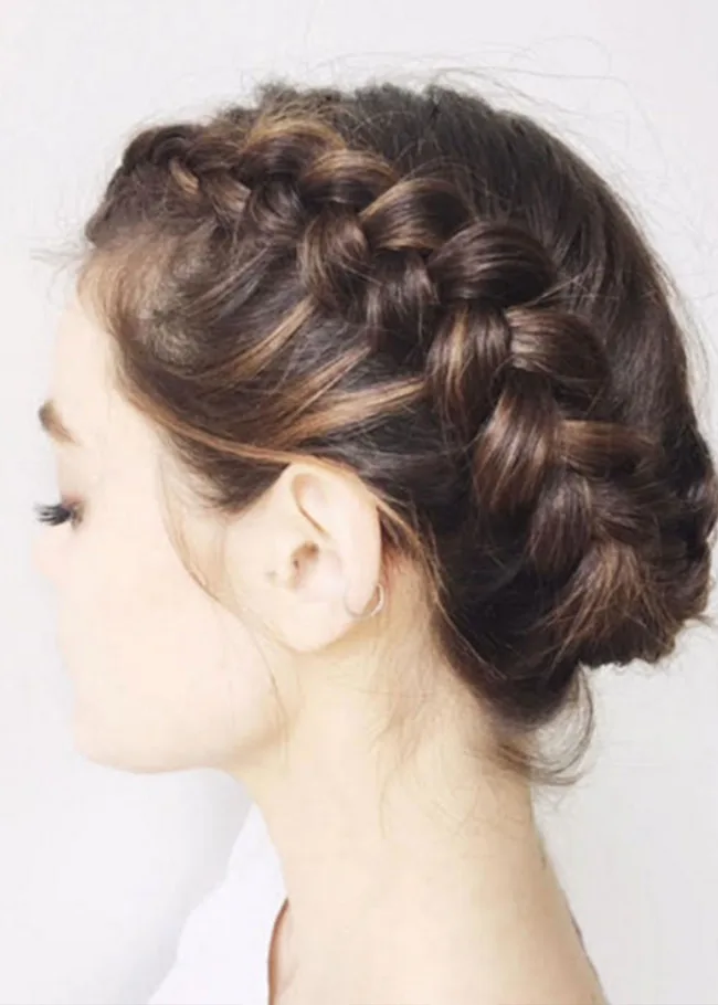 Person with braided hairstyle seen from the side, wearing small hoop earring.
