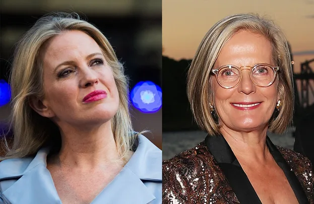 Two women, one with long blonde hair in a blue coat, and another with short blonde hair and glasses, smiling.