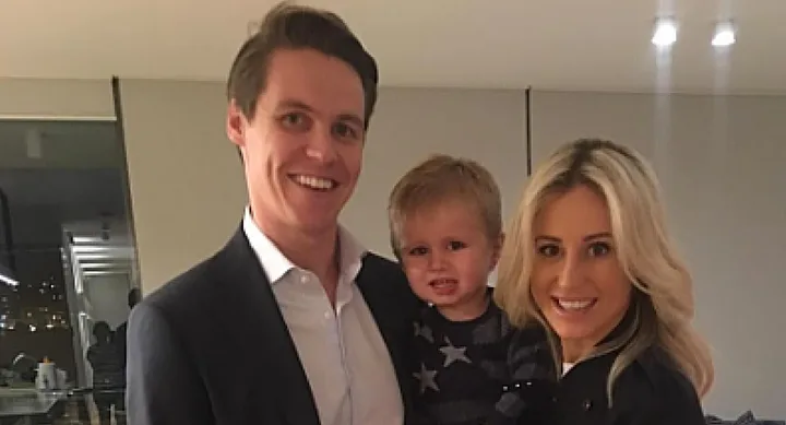 A smiling couple holding a young child in an indoor setting with modern decor.