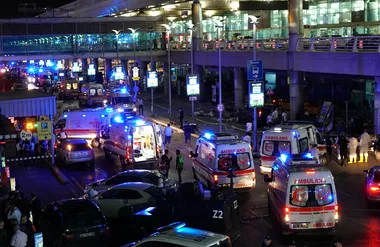 Outdoor scene with multiple ambulances and emergency personnel responding at night.