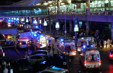 Outdoor scene with multiple ambulances and emergency personnel responding at night.