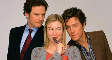Three people pose closely; the woman in the center holds a pen, while the men on either side look toward her.