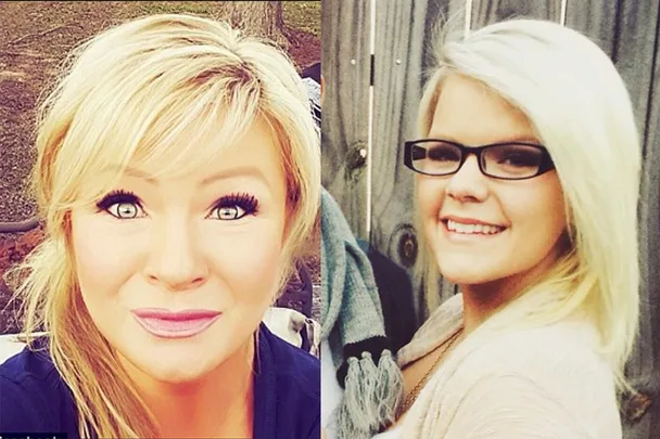 Two women with blonde hair smile, one wears glasses, standing outdoors with a wooden fence background.
