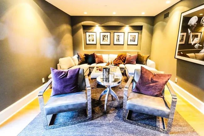 Cozy modern living room with gray couches, purple pillows, and framed black-and-white photos on the walls.
