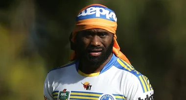 Rugby player in a blue and yellow jersey with an orange headband, outdoors under sunlight.