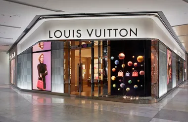 Exterior of a Louis Vuitton store with colorful window displays and a large brand sign above the entrance.