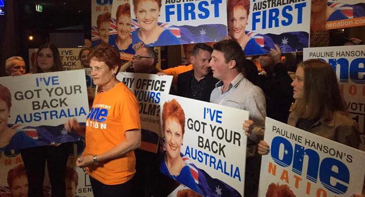 Group holding campaign posters that read "I've Got Your Back Australia" and "One Nation" with a woman in an orange shirt.