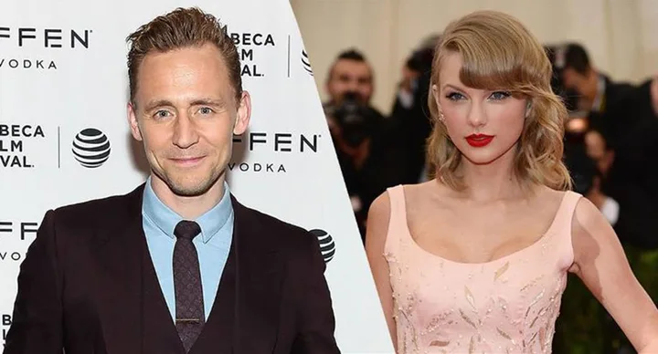 Two individuals in formal attire smiling at a red carpet event, one in a suit and tie, the other in a pink dress.