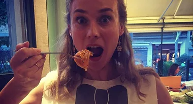 Person in a restaurant holding a fork with spaghetti, looking surprised.