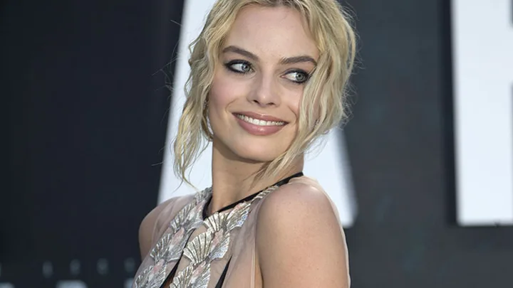 I don't know who this is, but it's a woman with blonde hair smiling at an event, wearing a dress with leaf designs.